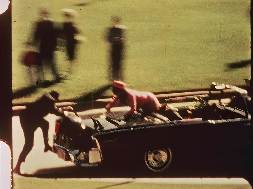 Fotograma de la grabación en el que Clint Hill se sube al coche presidencial para proteger a Jackie Kennedy
