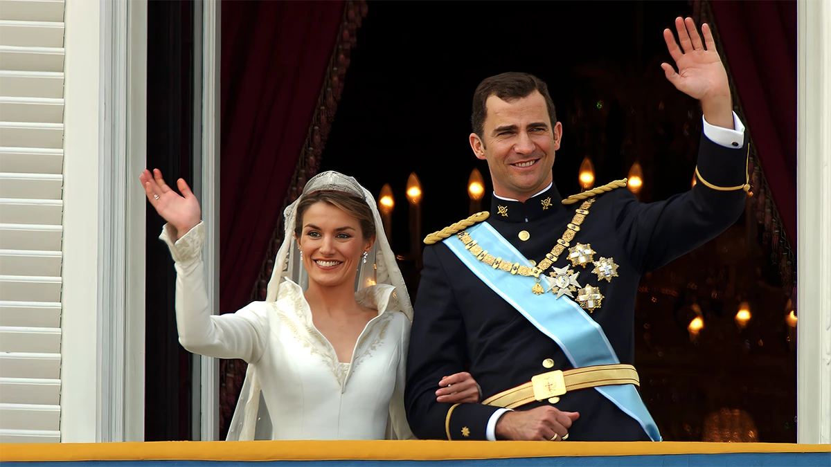 Don Felipe y Doña Letizia saludan desde el balcón del Palacio Real, donde se dieron un cariñoso beso