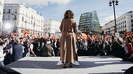 Isabel Díaz Ayuso, de espaldas, interviene ante los manifestantes congregados en la Puerta del Sol de Madrid